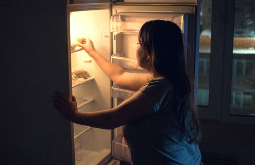 Woman getting something out of the refrigerator during the night