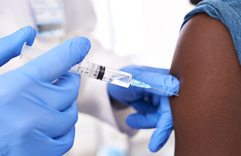 A closeup of a gloved healthcare provider injecting a vaccine into a patient's arm
