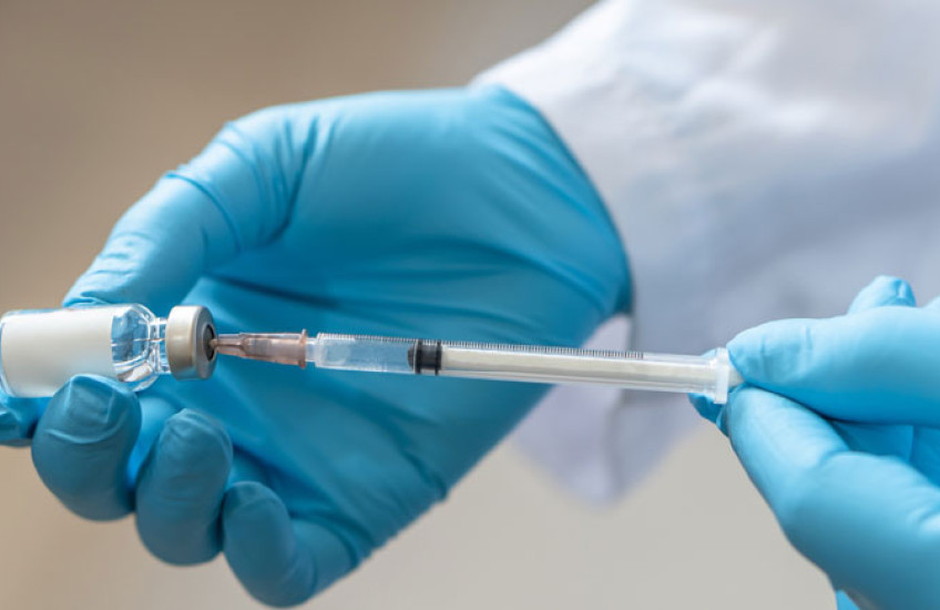 Blue-gloved hands holding a vaccine syringe