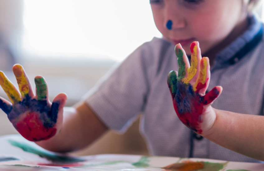A young child's paint-covered hands.