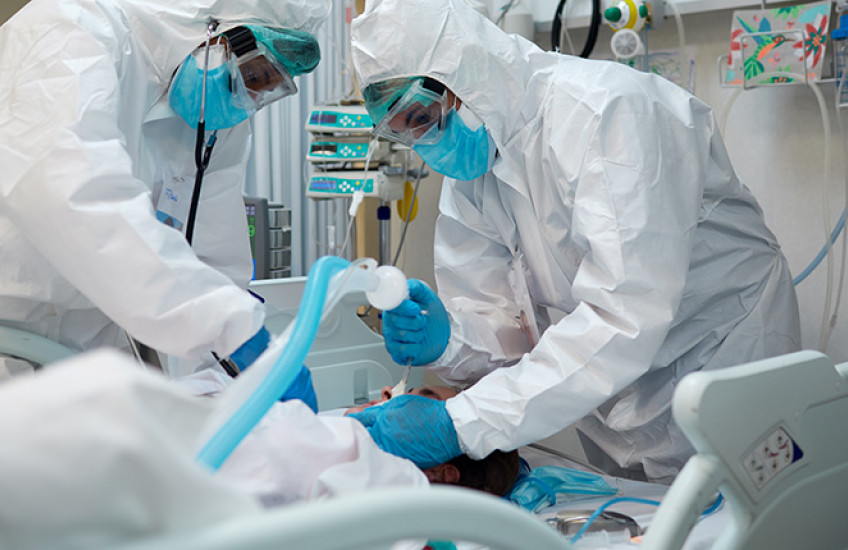 two health care workers intubating a patient with covid-19