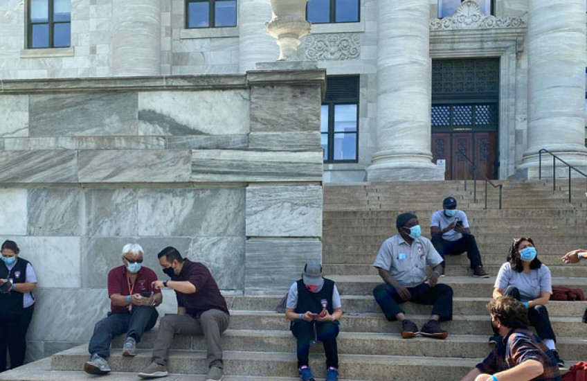 Los investigadores y el personal de conserjería del HMS se reúnen en los escalones de Gordon Hall en el HMS Quad