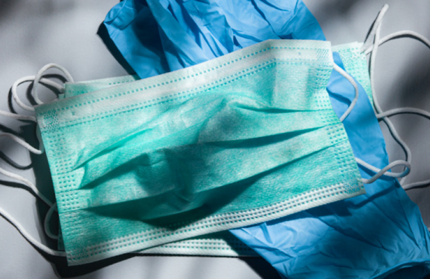 A mask and gloves on a table in dappled light