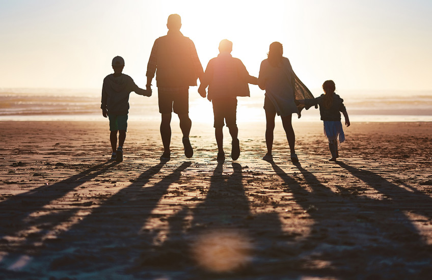 Silhouette of a family going for a walk together along the beach