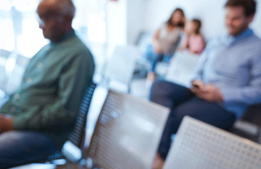 A blurry image of people in a waiting room.