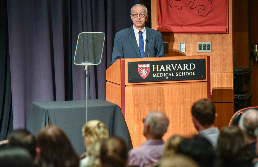 A person standing at a podium with a crowd of people watching