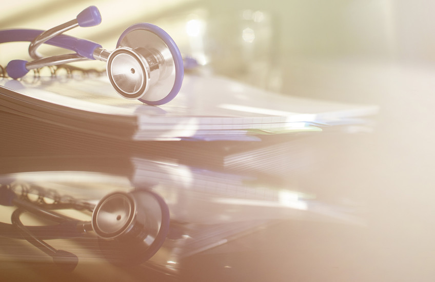 Photograph with soft filter; a stethoscope on a desk with a reflection on the desktop, no doctor there