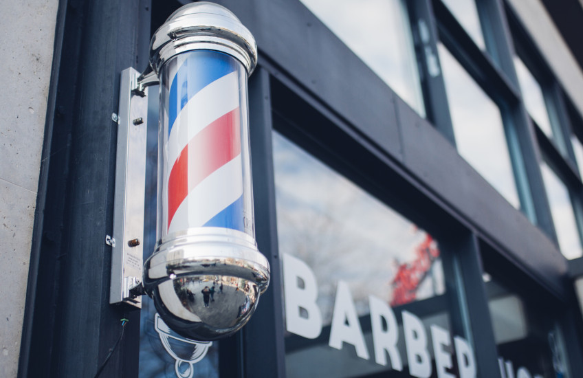 Photo of striped barbershop pole mounted on door of shop