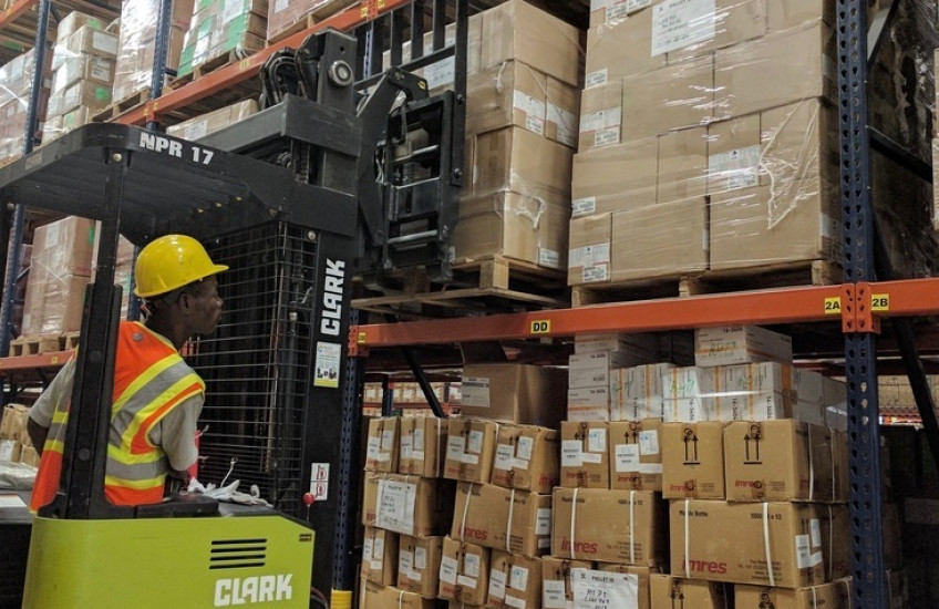 A man operates a forklift loaded with boxes in a warehouse.
