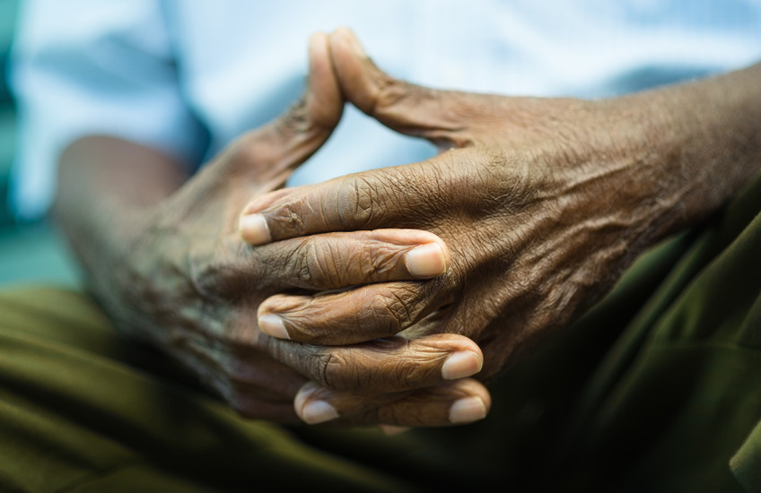 Closeup of hands of elderly Black man sitting on bench