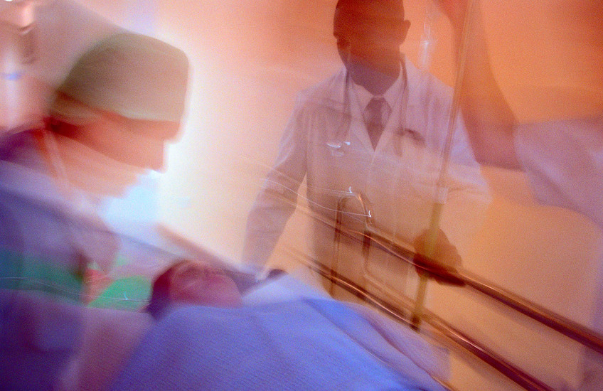Motion blurred photo of hospital staff wheeling a patient on a gurney down a corridor