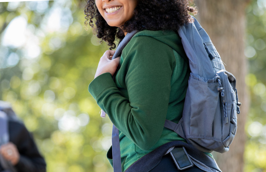 Young woman outdoors with backpack wearing a glucose monitor