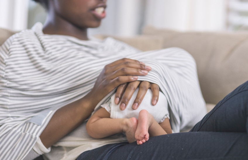 baby under woman's shirt breastfeeding