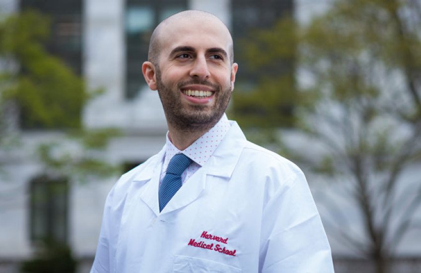 Headshot of Meshkin wearing a white coat with HMS logo with Quad behind him