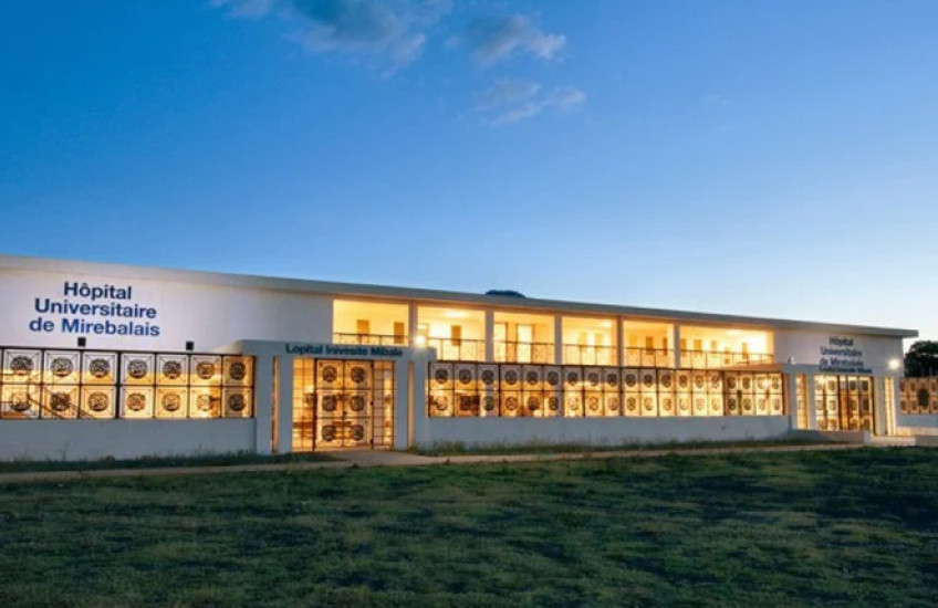A white hospital building with golden glowing windows under a dark sky.