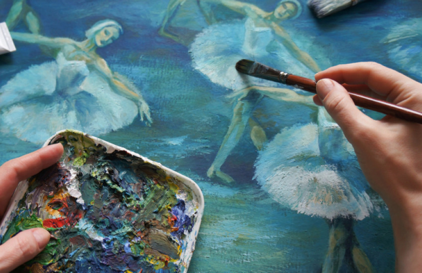 Close-up of a painter's hands working on a picture of dancers.
