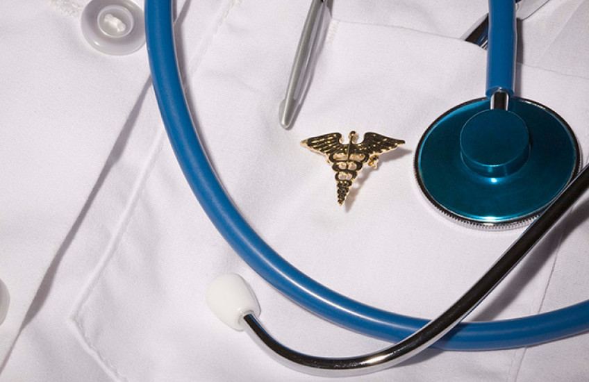 photo of stethoscope and rod of Aesculapius on white coat