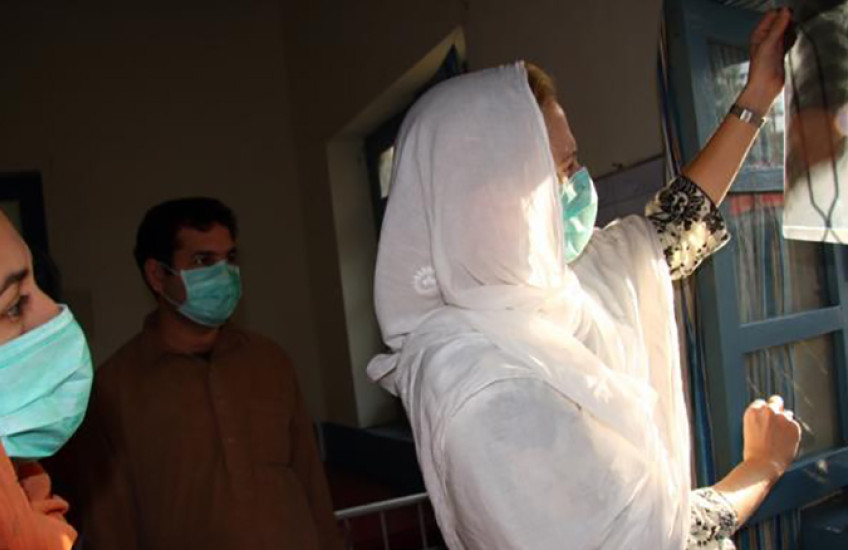 Three people in surgical masks examine an x-ray of a person's lungs.