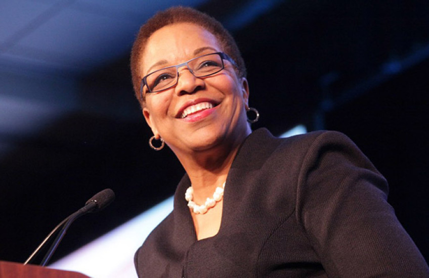 Joan Reede standing behind a podium, smiling