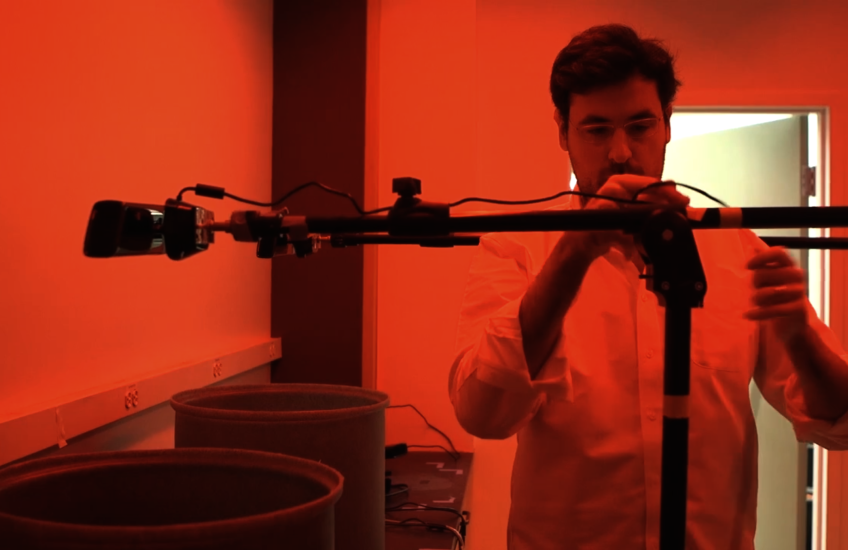 red-lit photograph of a researcher adjusting a camera on a pole