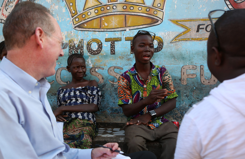 Four people having a conversation sit in front of a colorful mural