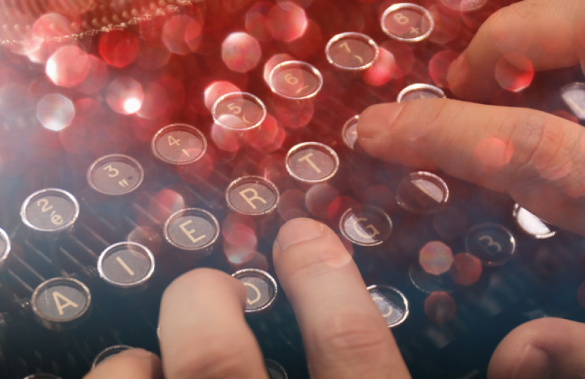 Hands on a typewriter keyboard.