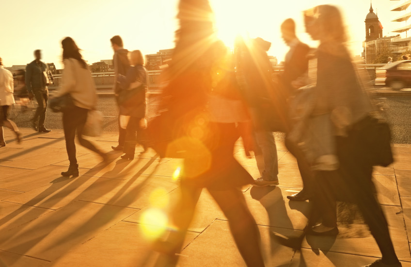 Motion blurred photo of people walking backlit by the sun.