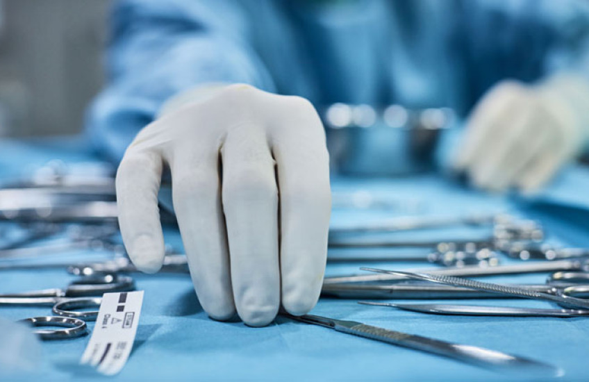 Hands reaching for surgical tools.