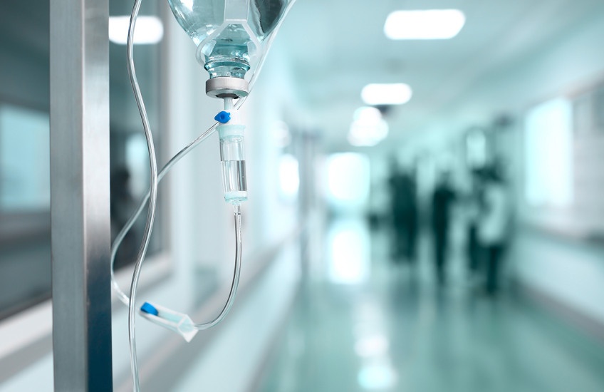A bag of IV medicine hangs in a lonely hallway.
