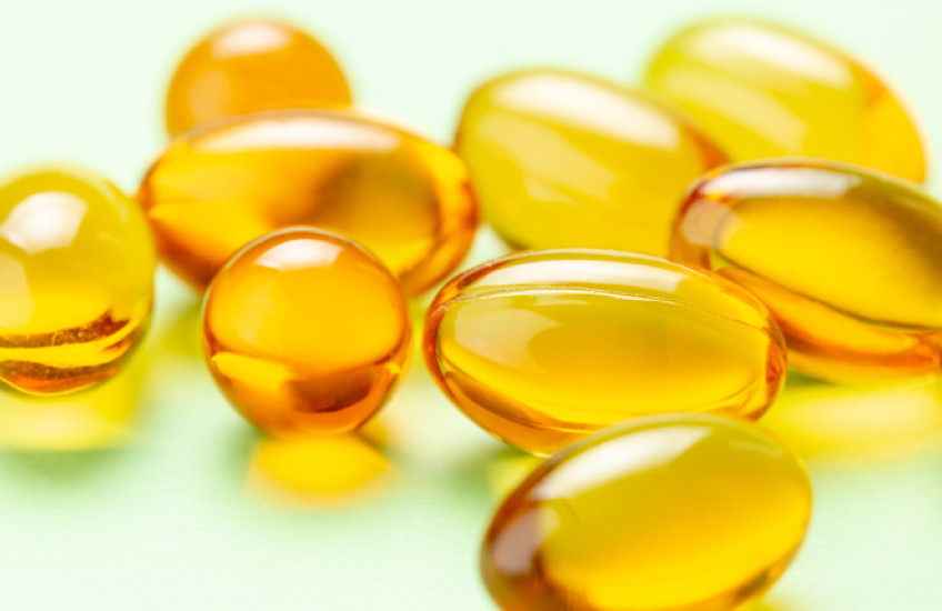 photo of vitamin D capsules on a light green background