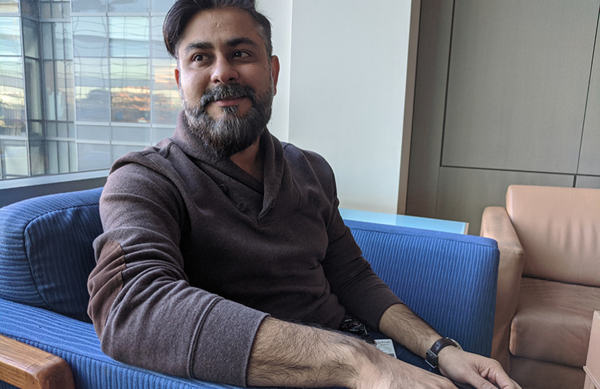 Portrait photo of young bearded man sitting in armchair in front of a window
