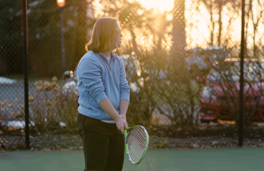 Silhouette of a male teen with Down syndrome holding a tennis racket
