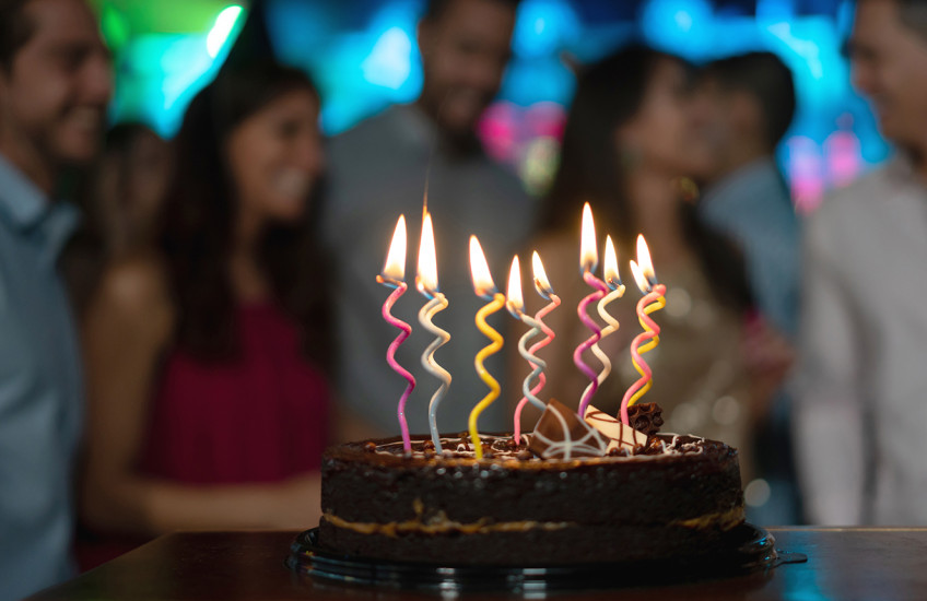 Close-up on a candle-lit cake on a table at a birthday party 