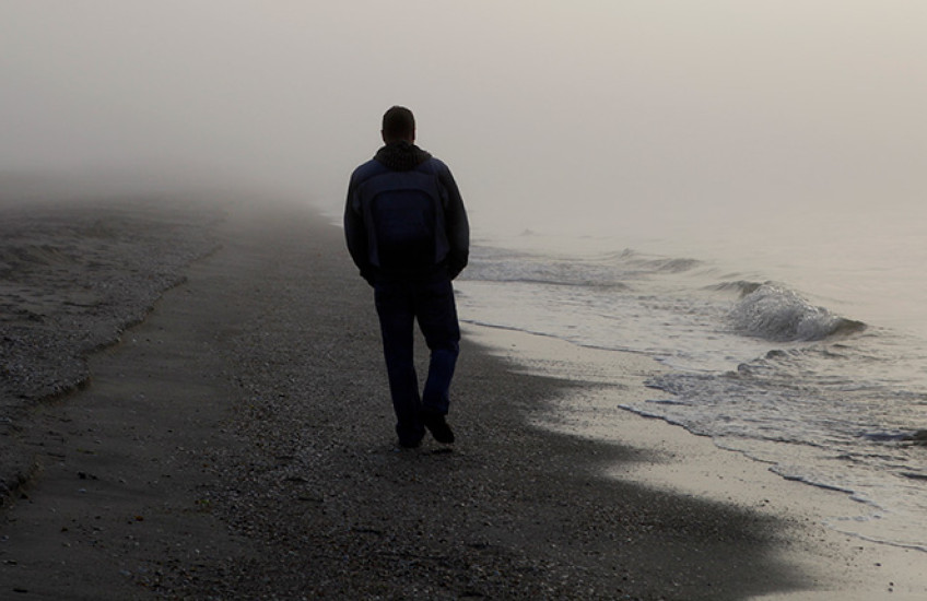 photo with silhouette of person walking on a foggy beach