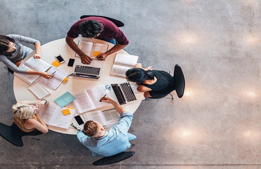 Photo of a study group at a table with computers, books, and notes