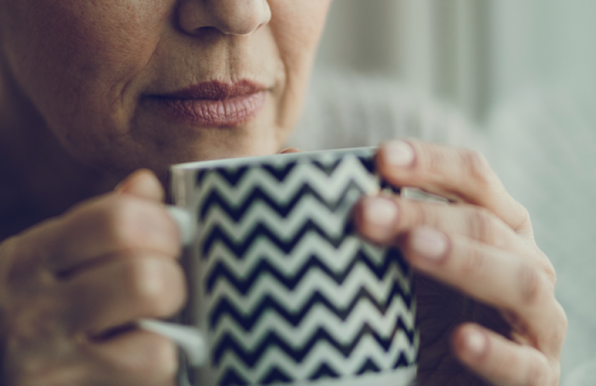 close up of older woman holding coffee mug to her nose