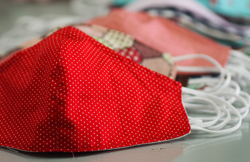 A group of colorful masks for protection from covid-19 sit on a desk.