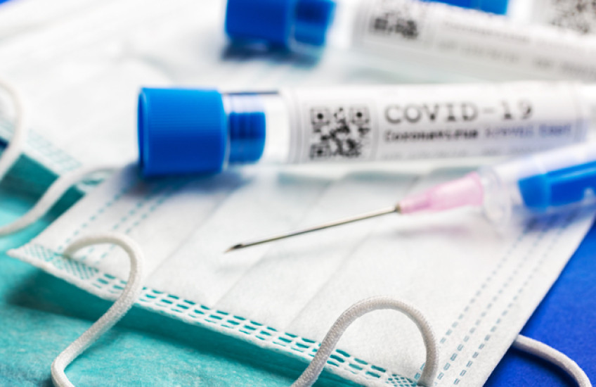 photo of medical mask, vials marked covid-19 and needle