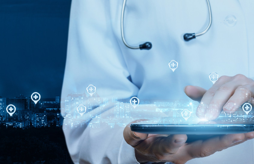 A stock photo of a doctor's torso and hands holding and operating a digital tablet device.