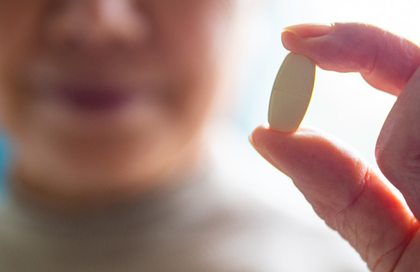 blurred face of senior women showing a pill