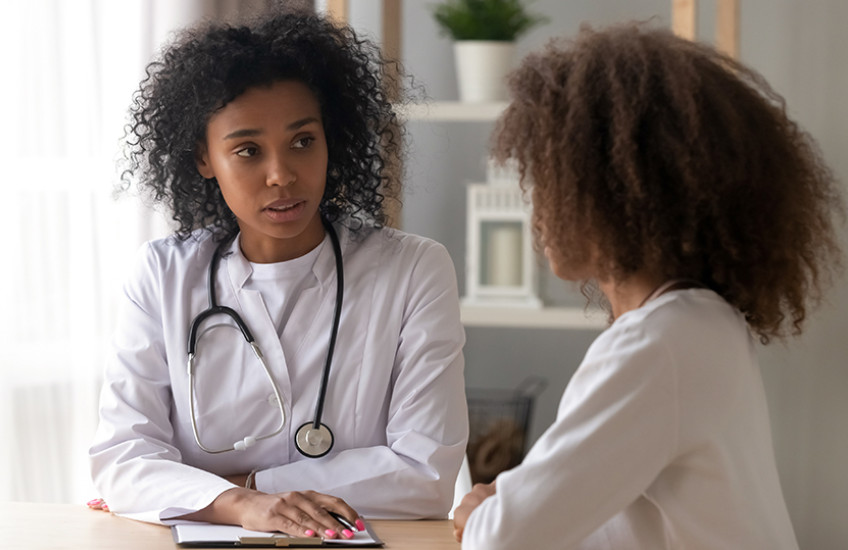 Young Black doctor has serious conversation with pediatric patient of color