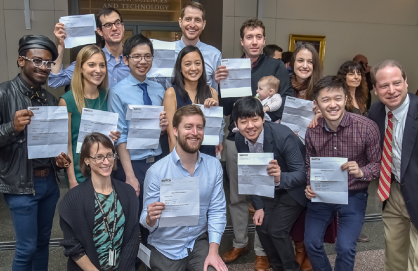 Group of students smiling and holding up their Match Day letters