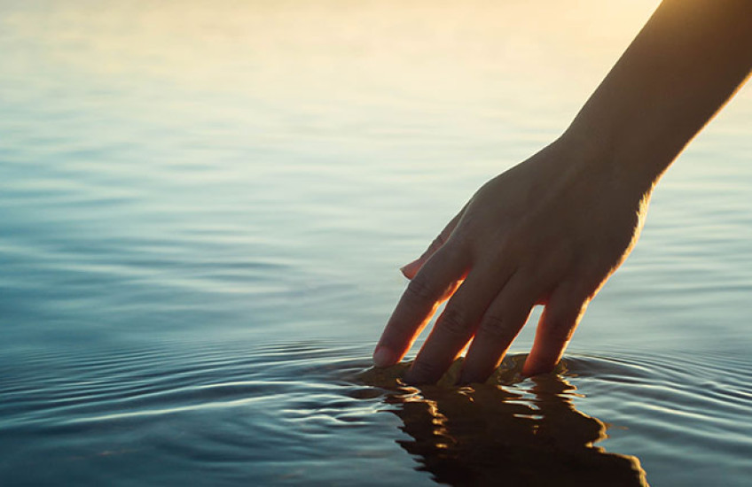 Photo of hand touching a pool of water