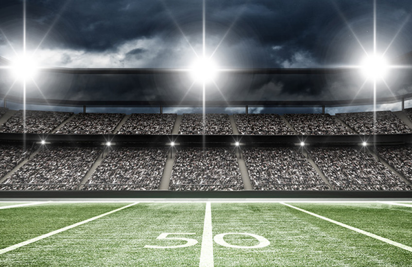 football stadium showing 50 yard line, crowd in seats and lights