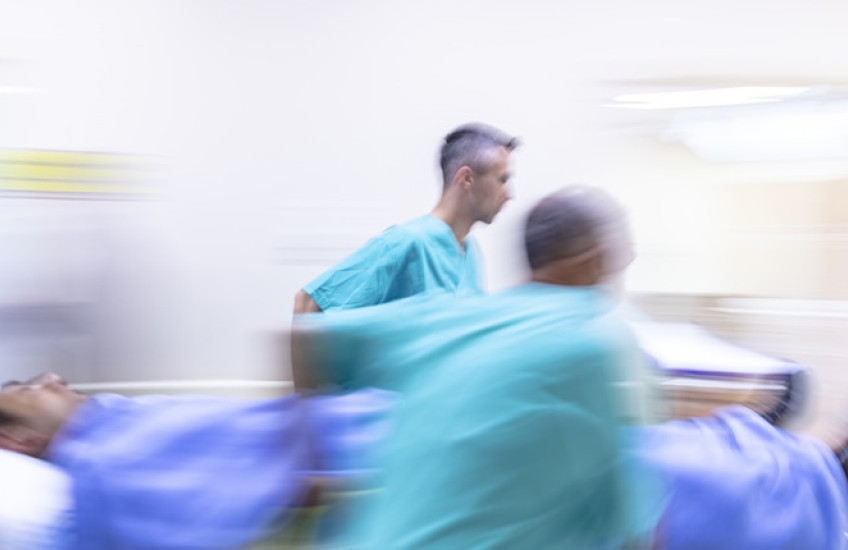 Medical staff hurry through a hospital with a patient on a gurney.