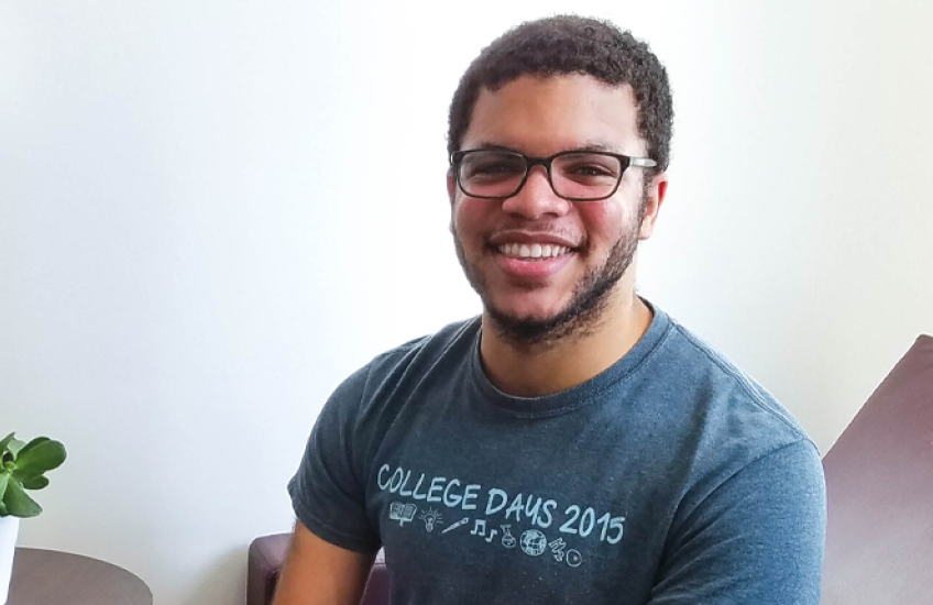 head shot of du maine sitting on a couch with succulent plant nearby