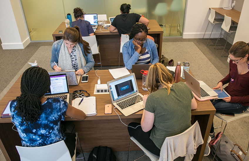 seven students studying at two desks in new student study center