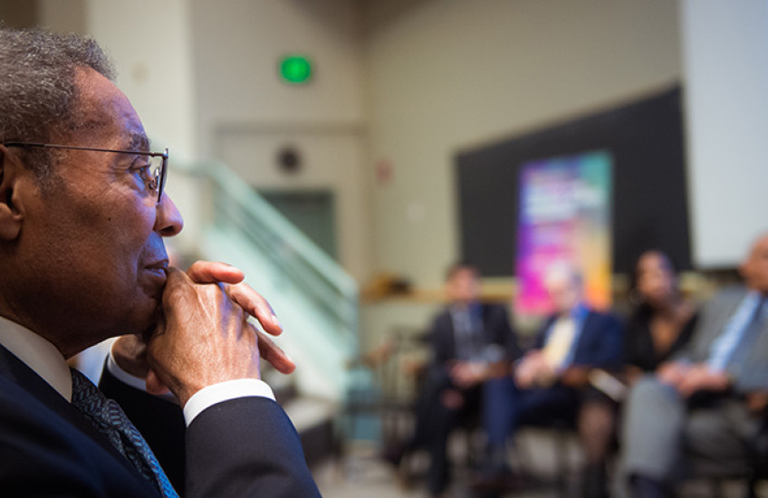 Poussaint looking on with panelists blurred in background