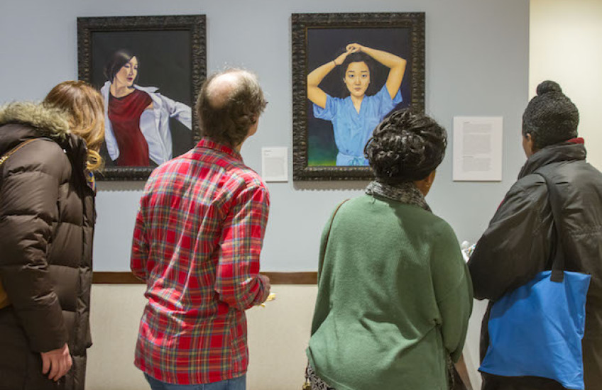 People viewing Chen paintings in the dean's office 