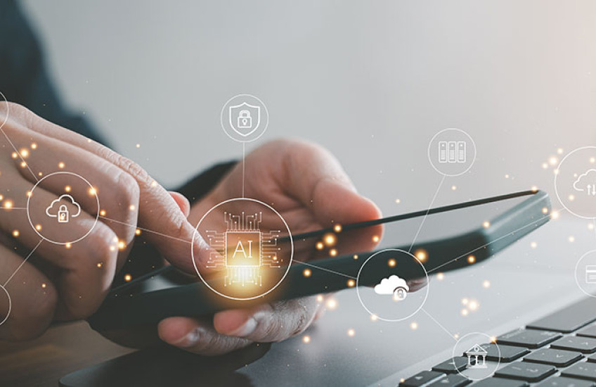 photo of a user looking at a smartphone screen in front of a computer